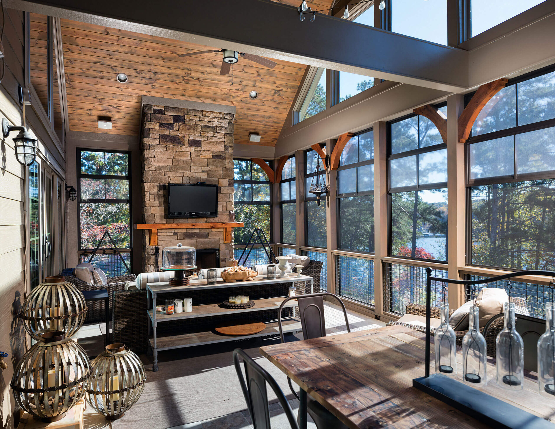 Lakefront sunroom by Bell Construction — stone fireplace, wood-beamed cathedral ceiling, full glass walls to Lake Lanier