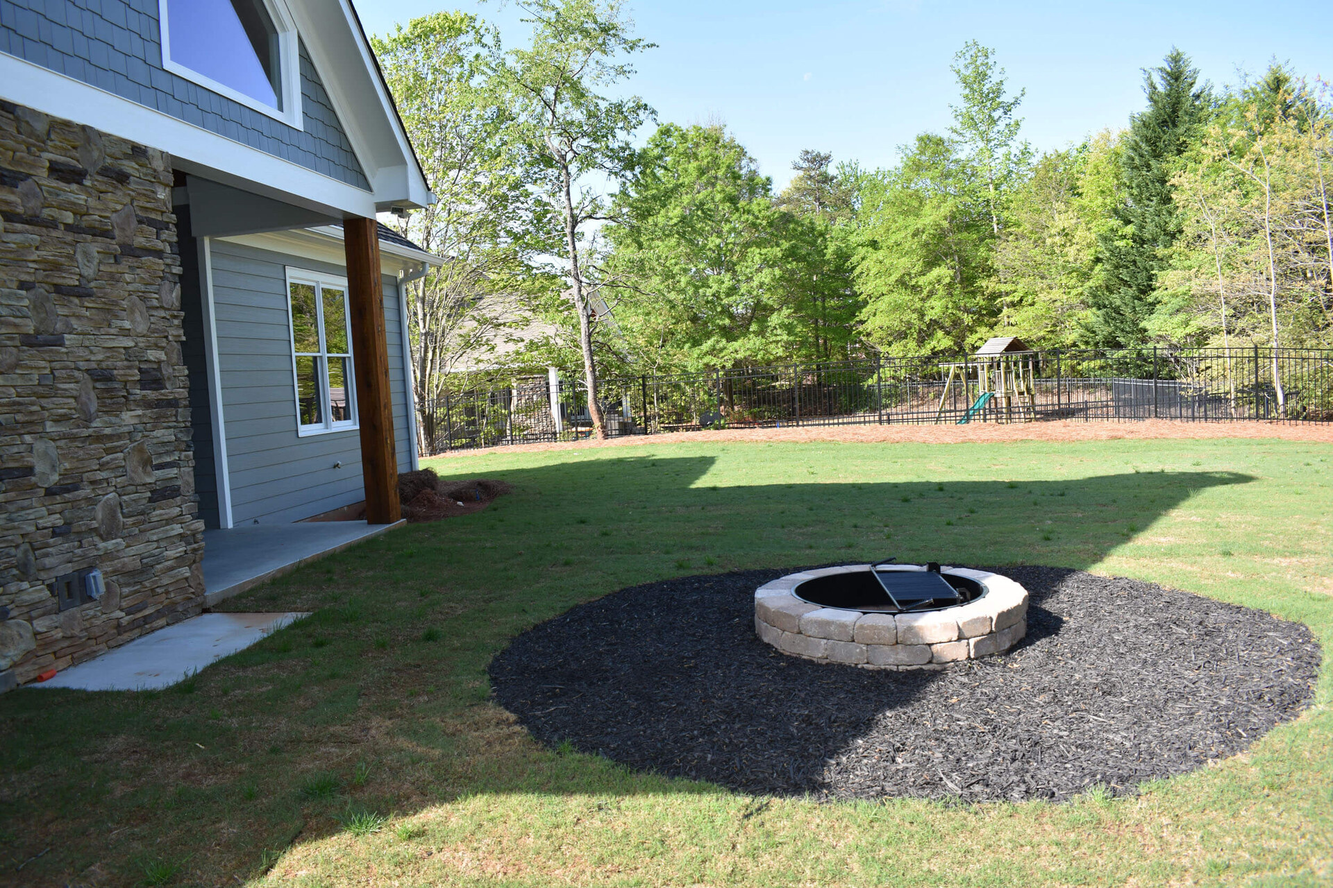 Outdoor living space by Bell Construction — covered porch, stone fireplace, lake-view dining
